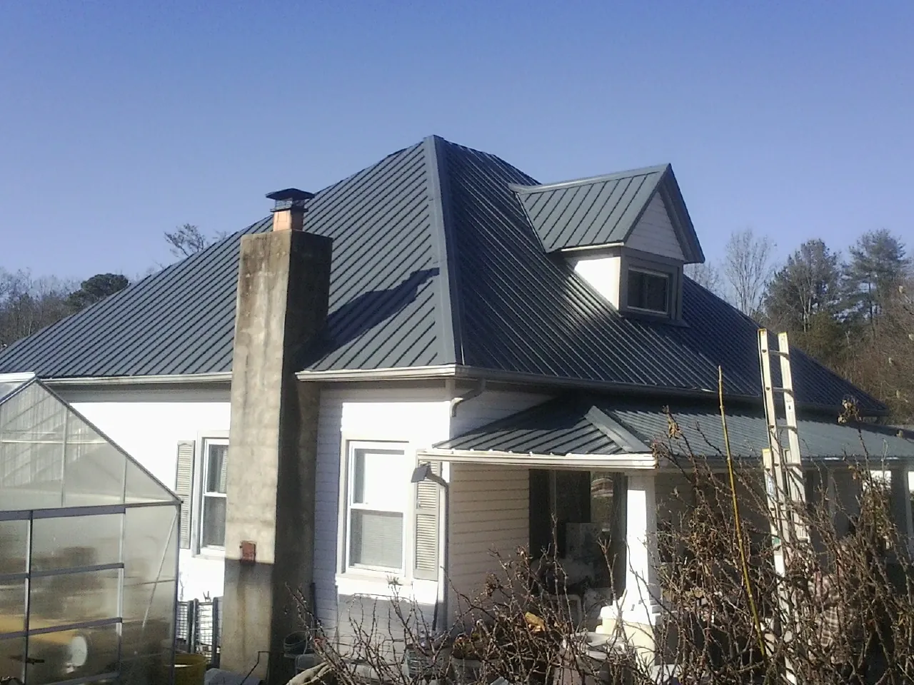 Dark blue standing seam metal roof on a white farmhouse with dormer — Slate & Tile Roof Repair by Roofing Brothers in Belford