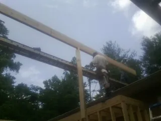 Carpenter setting a ridge beam over a new addition frame — Ice Dam Removal by Roofing Brothers in Belford