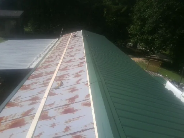 Old rusted panels beside newly installed green metal roofing — Wind Damage Roof Repair by Roofing Brothers in Belford