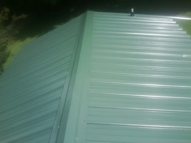 New green metal panels meeting at the ridge of a roof — Flat Roof Repair work by our crew in Belford