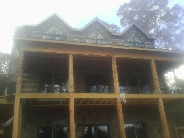Dormers and porch framing on a large log home under construction — Roof Coating work by our crew in Belford