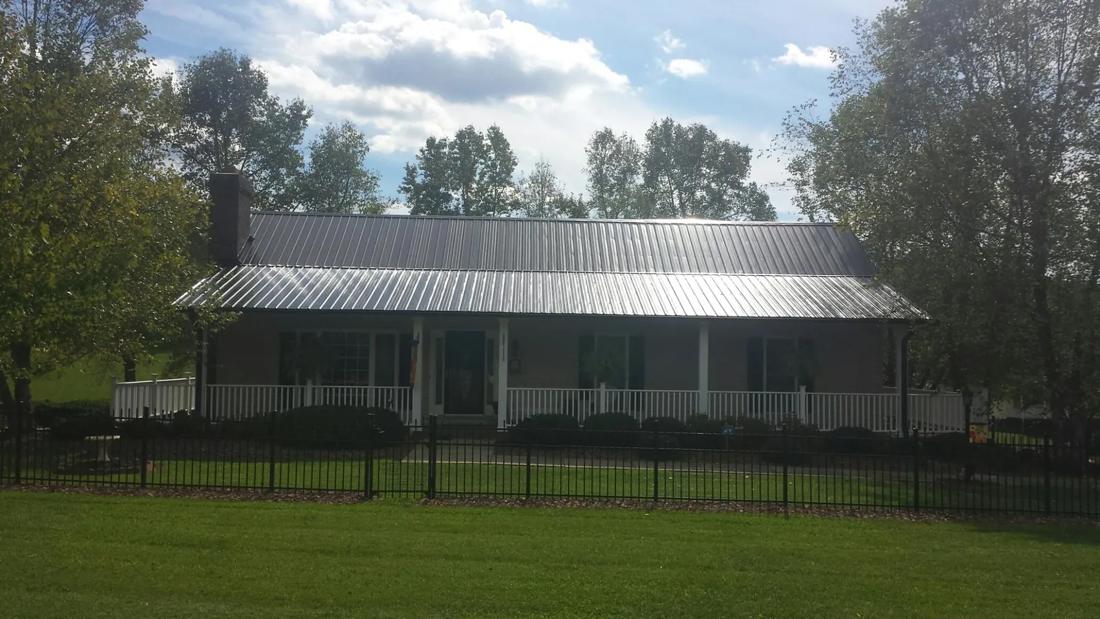 Gray metal roof on a brick ranch with a full width front porch — Gutter Guard Installation work by our crew in Belford