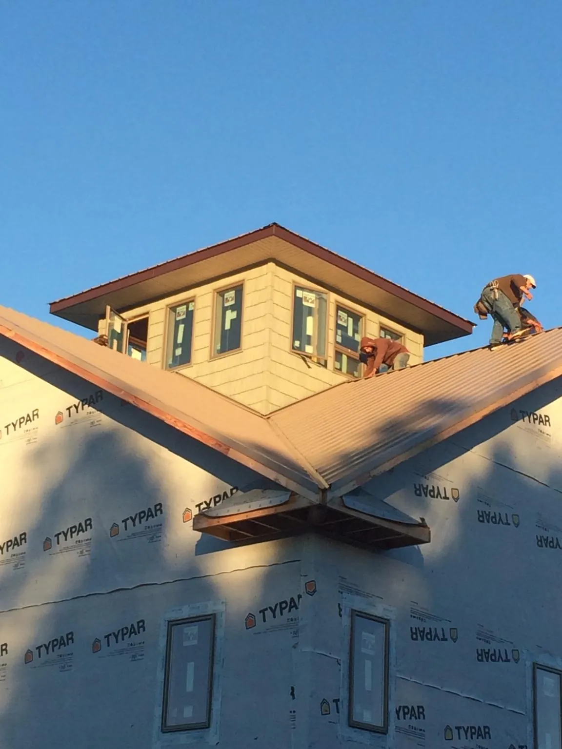 Roofers working around a rooftop cupola on a new metal roof at sunset — Roof Waterproofing in Belford by Roofing Brothers